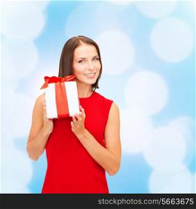 christmas, holidays, valentine&#39;s day, celebration and people concept - smiling woman in red dress with gift box over blue lights background