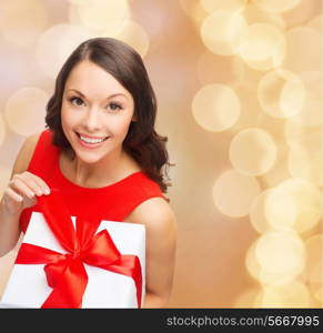 christmas, holidays, valentine&#39;s day, celebration and people concept - smiling woman in red dress with gift box over beige lights background