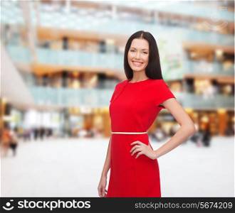 christmas, holidays, valentine&#39;s day, celebration and people concept - smiling woman in red dress over shopping center background