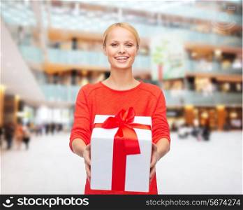 christmas, holidays, valentine&#39;s day, shopping and people concept - smiling woman in red clothes with gift box over lights background
