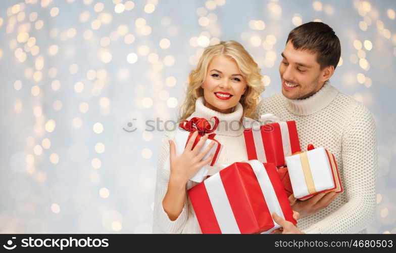 christmas, holidays, valentine's day, celebration and people concept - smiling man and woman with presents over lights background