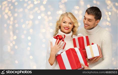 christmas, holidays, valentine's day, celebration and people concept - smiling man and woman with presents over lights background