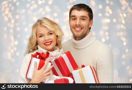 christmas, holidays, valentine's day, celebration and people concept - smiling man and woman with presents over lights background