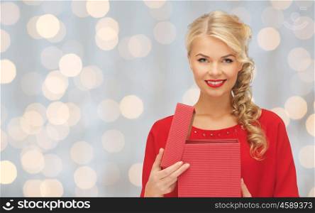 christmas, holidays, valentines day, birthday and people concept - happy smiling woman in red dress with gift box over lights background