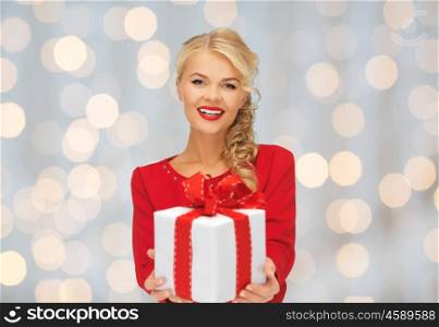 christmas, holidays, valentines day, birthday and people concept - happy smiling woman in red dress with gift box over lights background