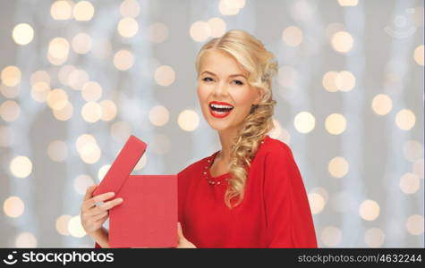 christmas, holidays, valentines day, birthday and people concept - laughing woman in red dress with gift box over lights background