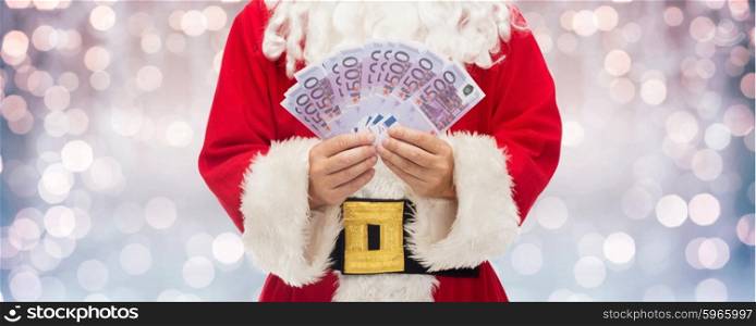christmas, holidays, winning, currency and people concept - close up of santa claus hands holding euro money over lights background