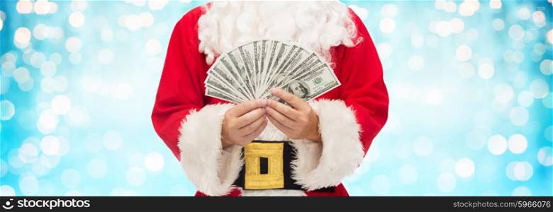 christmas, holidays, winning, currency and people concept - close up of santa claus hands holding dollar money over blue lights background