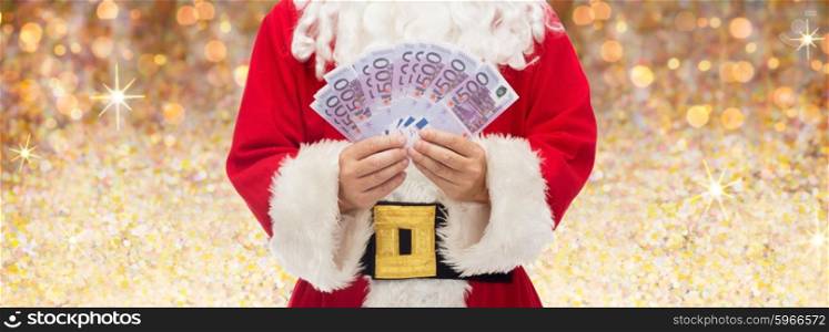 christmas, holidays, winning, currency and people concept - close up of santa claus with euro money over lights or golden glitter background
