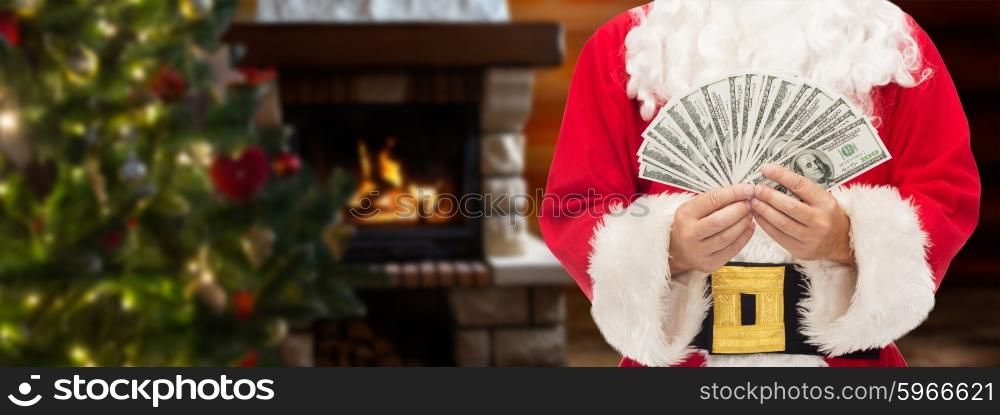 christmas, holidays, winning, currency and people concept - close up of santa claus with dollar money over living room with fireplace and christmas tree background