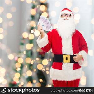 christmas, holidays, winning, currency and people concept - man in costume of santa claus with euro money over tree lights background