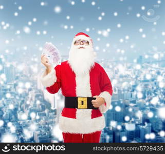 christmas, holidays, winning, currency and people concept - man in costume of santa claus with euro money over snowy city background