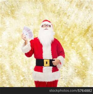 christmas, holidays, winning, currency and people concept - man in costume of santa claus with euro money over yellow lights background