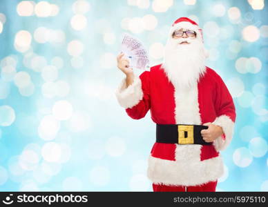 christmas, holidays, winning, currency and people concept - man in costume of santa claus with euro money over blue holidays lights background