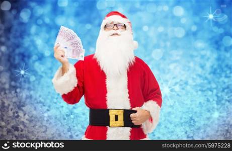 christmas, holidays, winning, currency and people concept - man in costume of santa claus with euro money over blue glitter or lights background