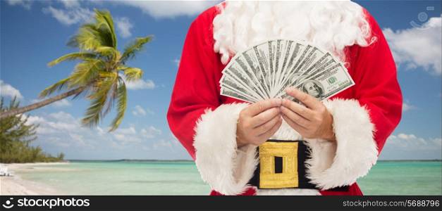 christmas holidays, winning, currency, travel and people concept - close up of santa claus with dollar money over tropical beach background