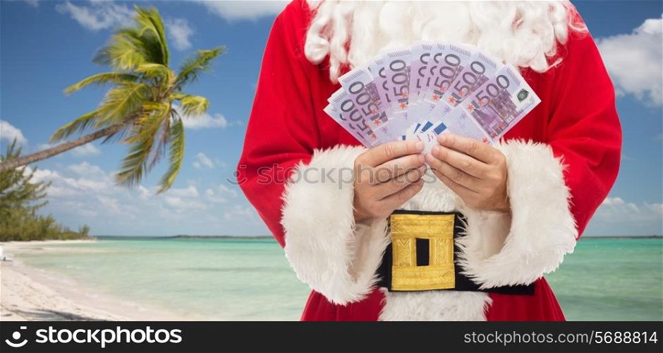 christmas holidays, winning, currency, travel and people concept - close up of santa claus with euro money over tropical beach background