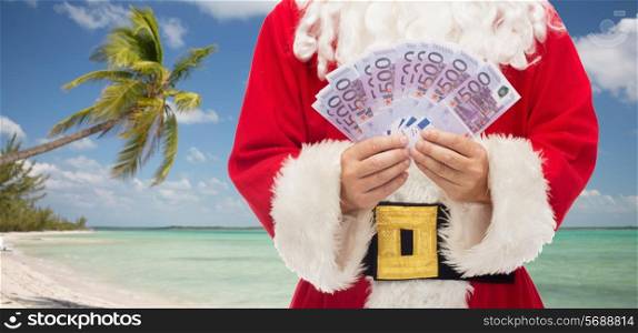 christmas holidays, winning, currency, travel and people concept - close up of santa claus with euro money over tropical beach background