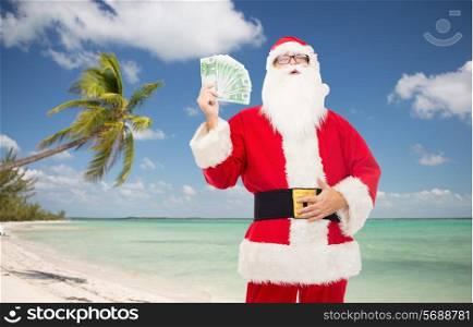 christmas holidays, winning, currency, travel and people concept - man in costume of santa claus with euro money over tropical beach background