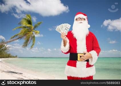 christmas holidays, winning, currency, travel and people concept - man in costume of santa claus with dollar money over tropical beach background