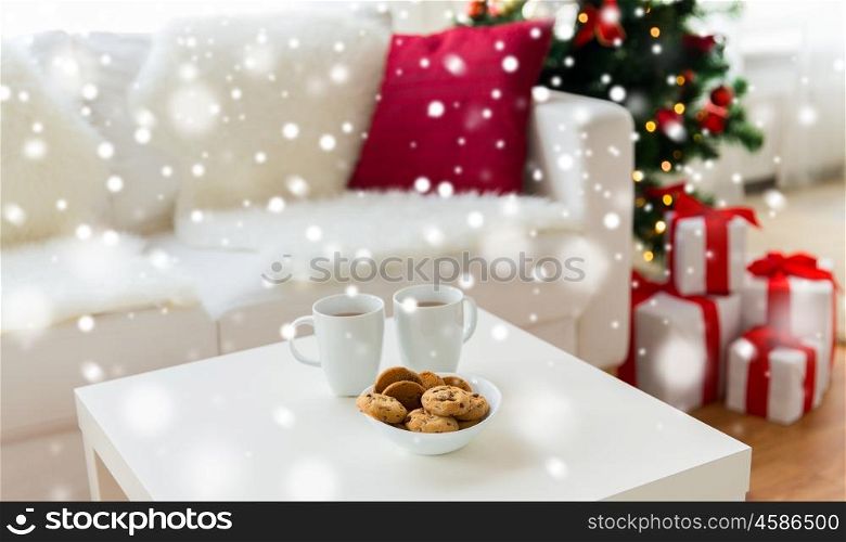 christmas, holidays, winter, celebration and still life concept - close up of cookies and cups with hot chocolate or cocoa drink on table at home