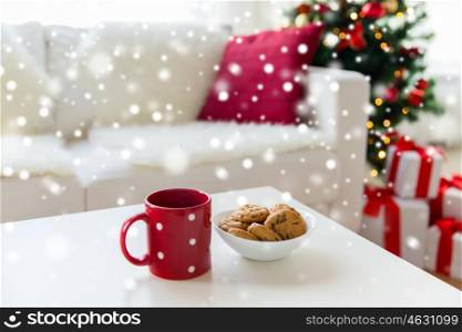 christmas, holidays, winter, celebration and still life concept - close up of oat cookies and red cup on table at home