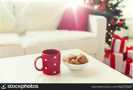 christmas, holidays, winter, celebration and still life concept - close up of oat cookies and red cup on table at home. close up of christmas cookies and red cup on table