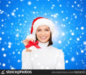 christmas, holidays, winter, happiness and people concept - smiling woman in santa helper hat with jingle bells over blue snowy background