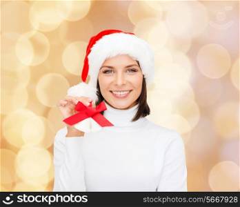 christmas, holidays, winter, happiness and people concept - smiling woman in santa helper hat with jingle bells over beige lights background