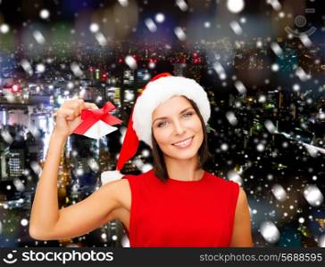 christmas, holidays, winter, happiness and people concept - smiling woman in santa helper hat with jingle bells over snowy night city background