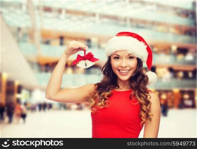 christmas, holidays, winter, happiness and people concept - smiling woman in santa helper hat with jingle bells over shopping center background