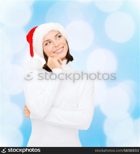 christmas, holidays, winter, happiness and people concept - thinking and smiling woman in santa helper hat over blue lights background