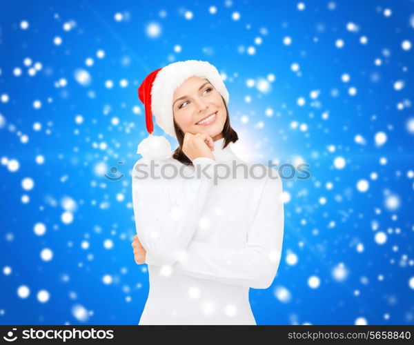 christmas, holidays, winter, happiness and people concept - thinking and smiling woman in santa helper hat over blue snowy background