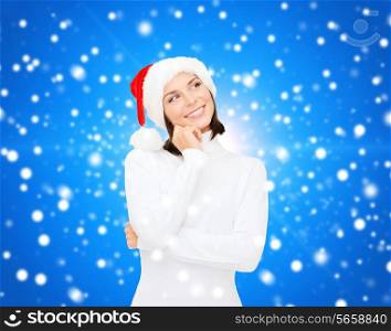 christmas, holidays, winter, happiness and people concept - thinking and smiling woman in santa helper hat over blue snowy background