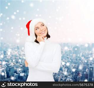 christmas, holidays, winter, happiness and people concept - thinking and smiling woman in santa helper hat over snowy city background