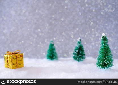 Christmas home decoration with Little handmade gift box in a snow covered miniature evergreen forest and bokeh light for copy space