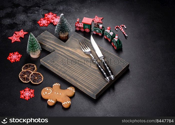 Christmas homemade gin≥rbread cookies, sπces and cutting board on dark background with©space for text top view. Christmas homemade gin≥rbread cookies, sπces and cutting board on dark background