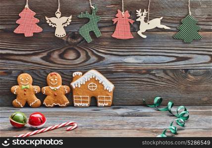 Christmas homemade gingerbread cookies and decoration on wooden background. Gingerbread house and couple - man and woman.
