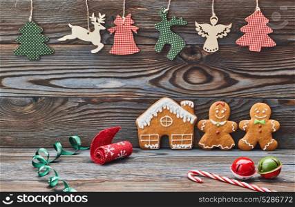 Christmas homemade gingerbread cookies and decoration on wooden background. Gingerbread house and couple - man and woman.