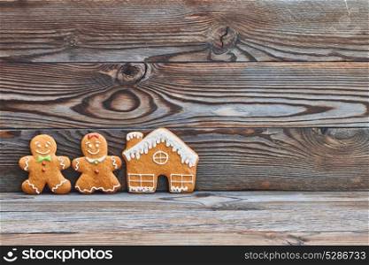 Christmas homemade gingerbread cookies on wooden background. Gingerbread house and couple - man and woman.