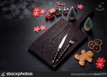 Christmas homemade gingerbread cookies, spices and cutting board on dark background with copy space for text top view. Christmas homemade gingerbread cookies, spices and cutting board on dark background
