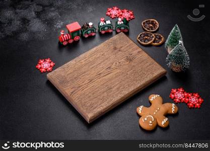 Christmas homemade gingerbread cookies, spices and cutting board on dark background with copy space for text top view. Christmas homemade gingerbread cookies, spices and cutting board on dark background