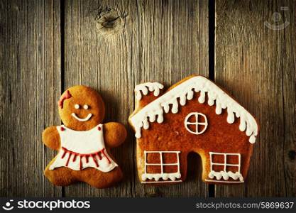 Christmas homemade gingerbread girl and house on wooden table