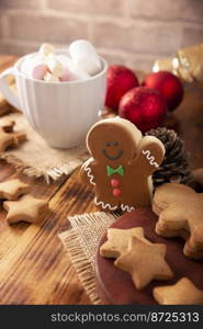 Christmas Homemade gingerbread man cookie and white cup with hot chocolate with marshmallows, traditionally made at wintertime and the holidays.