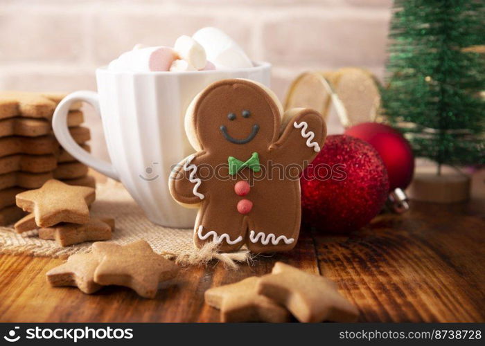 Christmas Homemade gingerbread man cookie and white cup with hot chocolate with marshmallows, traditionally made at wintertime and the holidays.