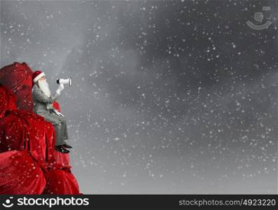 Christmas is coming!. Businessman in Santa costume shouting in megaphone
