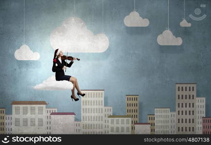 Christmas is coming. Woman in formal suit and Santa hat playing violin