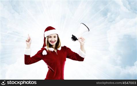 Christmas is coming. Young attractive Santa girl screaming in megaphone