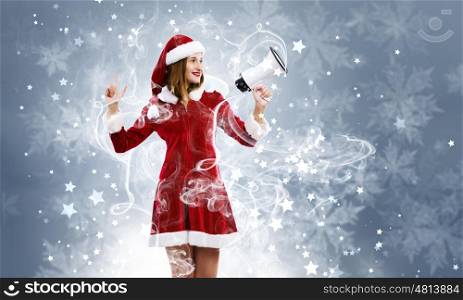 Christmas is coming. Young attractive Santa girl screaming in megaphone