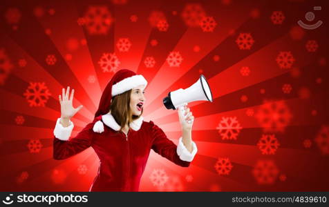 Christmas is coming. Young attractive Santa girl screaming in megaphone